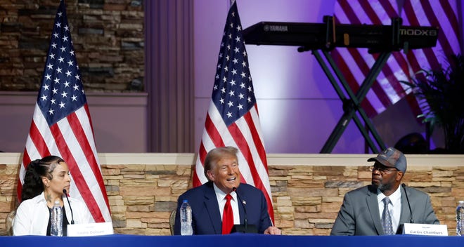 Former President Donald Trump talks during a roundtable discussion as invited guests, left to right, Itasha Dotson and Carlos Chambers, listen inside the 180 Church in Detroit on Saturday, June 15, 2024.