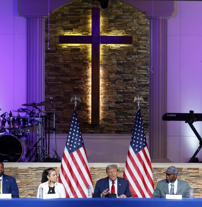 Former President Donald Trump talks during a roundtable discussion as invited guests, left to right, Itasha Dotson and Carlos Chambers, listen inside the 180 Church in Detroit on Saturday, June 15, 2024.