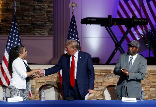 Former President Donald Trump thanks (L to R) some of the invited guests at the table, Itasha Dotson and Carlos Chambers inside the 180 Church in Detroit on Saturday, June 15, 2024.