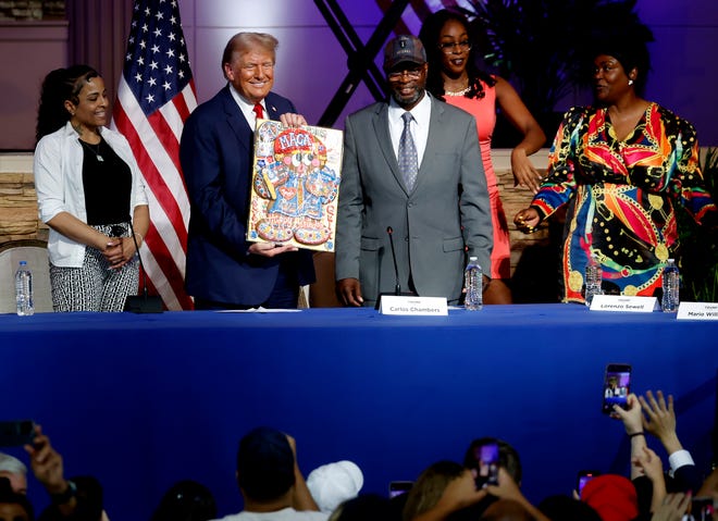 Former President Donald Trump shows off the decorated birthday cake cookie that was given to him after the crowd sang happy birthday to him following the roundtable discussion inside the 180 Church in Detroit on Saturday, June 15, 2024.