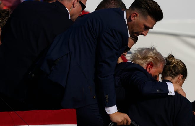 Republican presidential candidate, former U.S. President Donald Trump, is whisked away by the Secret Service after shots rang out at a Butler Farm Show Inc. campaign rally on July 13, 2024, in Butler, Pennsylvania. Trump slumped, and injuries were visible on the side of his head. Butler County District Attorney Richard Goldinger said the shooter and one audience member are dead, and another was injured.