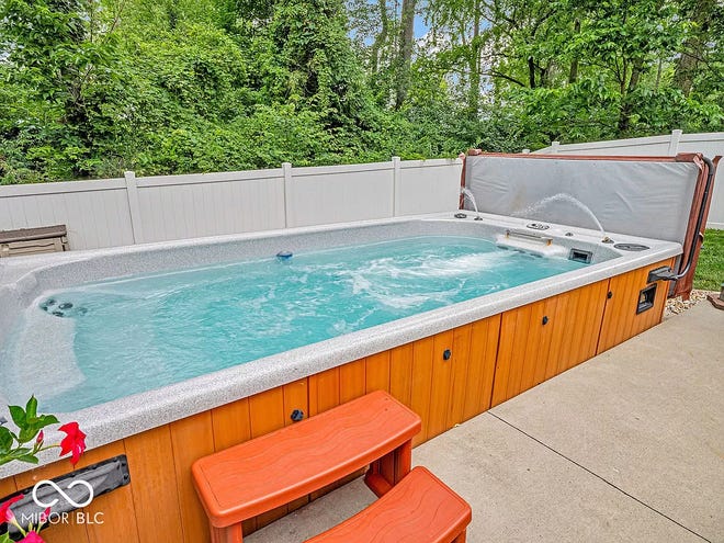 This home in Avon has tons of space inside and a backyard oasis outside with a swim spa and wooded backdrop.