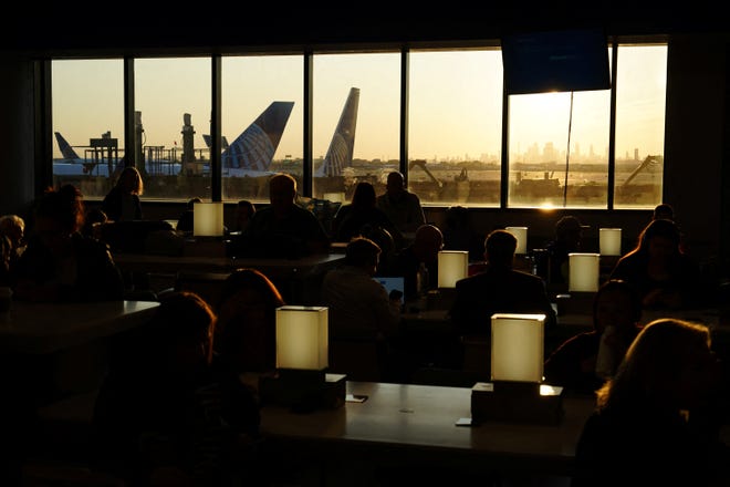 Travelers wait for delayed flights beneath a monitor displaying a blue error screen inside Terminal C in Newark International Airport, after United Airlines and other airlines grounded flights due to a worldwide tech outage caused by an update to Crowdstrike's "Falcon Sensor" software which crashed Microsoft Windows systems, in Newark, New Jersey, U.S., July 19, 2024.