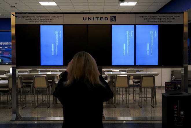 A traveler uses her mobile phone to photograph a departures board displaying blue error screens, also known as the "Blue Screen of Death" inside Terminal C in Newark International Airport, after United Airlines and other airlines grounded flights due to a worldwide tech outage caused by an update to Crowdstrike's "Falcon Sensor" software which crashed Microsoft Windows systems, in Newark, New Jersey, U.S., July 19, 2024.