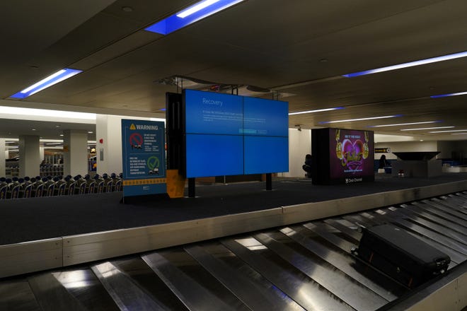 An item of checked luggage is seen near a monitor displaying a blue error screen, also known as the ?Blue Screen of Death? at a baggage claim area inside Terminal C in Newark International Airport, after United Airlines and other airlines grounded flights due to a worldwide tech outage caused by an update to Crowdstrike's "Falcon Sensor" software which crashed Microsoft Windows systems, in Newark, New Jersey, U.S., July 19, 2024.