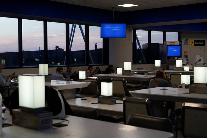 Travelers wait for their flights near monitors displaying blue error screens inside Terminal C in Newark International Airport, after United Airlines and other airlines grounded flights due to a worldwide tech outage caused by an update to Crowdstrike's "Falcon Sensor" software which crashed Microsoft Windows systems, in Newark, New Jersey, U.S., July 19, 2024.