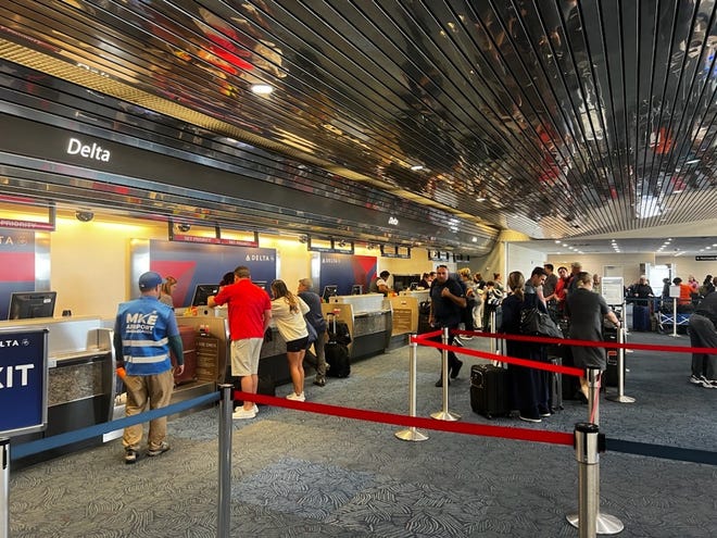 Flights are delayed and canceled at Milwaukee Mitchell International Airport due to a global tech outage, Friday, July 19, with RNC guests and security milling about in the main terminal.