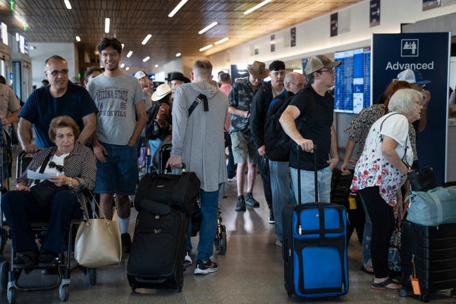 Passengers (right) wait in line at the Delta Air Lines ticket counter in Terminal 3, July 19, 2024, at Phoenix Sky Harbor International Airport.