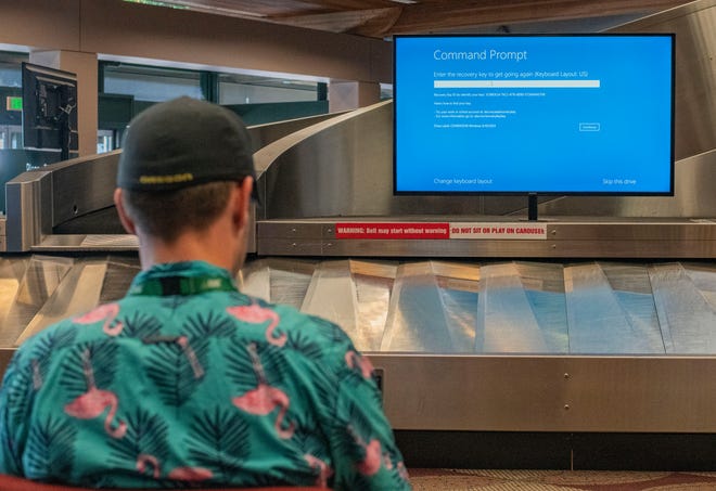 Jordan Rawls troubleshoots the advertising monitors at the baggage carousel at the Eugene Airport during the global Microsoft outage on Friday, July 18, 2024.